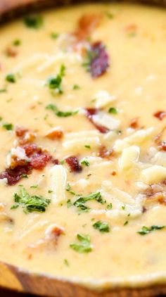 a close up of a bowl of food with cheese and bacon in it on a table