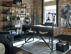 an industrial style home office with exposed brick walls and open shelving, leather chair, desk, and art on the wall