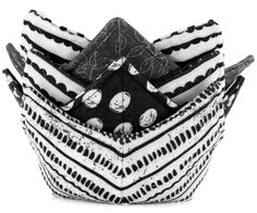 a black and white basket filled with different types of cloths on top of each other