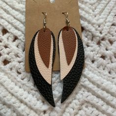 a pair of black, white and brown leather earrings