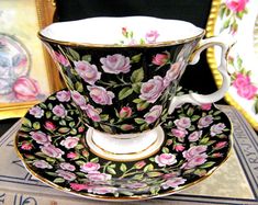 an antique tea cup and saucer with pink flowers on it, sitting on a table