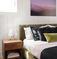 a bedroom with a bed, nightstand and painting on the wall above it's headboard