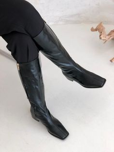 a woman in black boots is sitting down