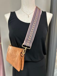 a woman wearing a black top with a brown leather purse on her shoulder and a pink braided belt around the waist