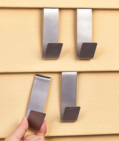 a hand is holding the door handle to an outside set of metal handles on a yellow house