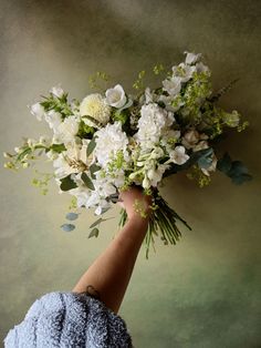 a hand holding a bouquet of white flowers