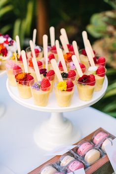 small desserts are arranged on a white plate with strawberries and raspberries