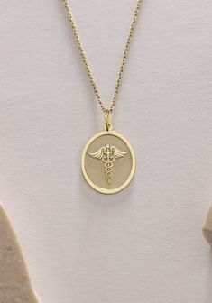 Gold Caduceus Pendant - Medical Gold Necklace ● Material of pendant: Solid Gold 14k ( REAL GOLD ) ● Metal Stamp: 14k ( REAL GOLD ) ● The pendant is available in 5 sizes: - 12x17 mm / 0,47 x 0,66 inches - 13x18 mm / 0,51 x 0,70 inches  In the photos - 14x19 mm / 0,55 x 0,74 inches  - 16x21 mm / 0,62 x 0,82 inches  - 18x24 mm / 0,70 x 0,94 inches ( In the photos the size is 13x18 mm / 0,51 x 0,70 inches ) ( Jump Ring inner diameter: 4 mm ) ● Material of chain: Solid gold 14k ( REAL GOLD ) It is thin and dainty and it is available in 4 sizes: - 40 cm / 15,75 inches ( Length ) - 45 cm / 17,72 inches ( Length ) In the photos - 50 cm / 19,68 inches ( Length ) - 55 cm / 21,65 inches ( Length ) ● Backside engraving is FREE ( Please use the personalization box for that.) ● If you want larger size, Personalized Symbolic Necklaces For Commemoration, Personalized Symbolic Necklace For Commemoration, Symbolic Charms Necklaces For Commemoration, Symbolic Charms Necklace For Commemoration, Symbolic Oval Charm Necklaces, Symbolic Oval Necklaces With Charms, Medical Pendant, Medical Alert, Gold Birthday