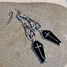 Add An Edgy Touch To Your Outfit With These Asymmetrical Dangle/Drop Earrings From Cascade Jewelry. The Midnight Black Enamel Coating And Pewter Base Metal Create A Gothic, Punk, And Bohemian Vibe. These Earrings Feature A Vampire Coffin And Hanging Bat Design With A Silver Cross Accent, Making Them Perfect For Those Who Love Art, Retro Style, And Costumes. The Hook Closure And Stainless Steel Metal Ensure Durability, While The 11 Mm Item Diameter And 71 Mm Item Length Make Them Suitable For Lob Emo Metal Earrings For Halloween, Black Metal Earrings For Alternative Fashion, Black Vampire Jewelry For Alternative Fashion, Black Metal Emo Earrings, Black Pierced Earrings For Alternative Fashion, Emo Metal Earrings For Parties, Black Earrings For Alternative Fashion, Emo Style Metal Earrings For Party, Gothic Metal Earrings For Alternative Fashion