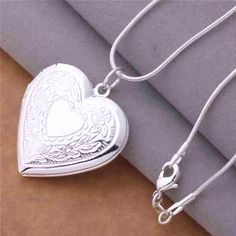 The perfect spot to keep your loved ones close. This beautiful heart shaped locket is finished in highly polished and has intricately detailed floral stamped designs along the front.The front opens on a hinge to hold photos or small momentos, a classic gift idea! Includes a smooth, 18 inch serpentine style chain. Occasions: Birthday, Holiday, Christmas, Mother's Day and Valentine's Day. Chain: 18 inch Serpentine style chain Material: Silver Plated (nickel free)brass Size: 29mm x 29mm Comes in a Jewelry Chains, Heart Photo, Sterling Silver Locket, Photo Locket Necklace, Heart Locket Necklace, Locket Pendant Necklace, Photo Locket, Silver Lockets, Silver Plated Necklace