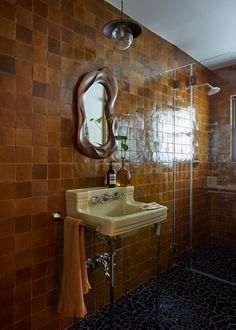 a bathroom with a sink, mirror and tiled walls