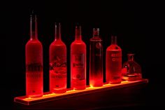 several bottles are lit up in the dark with red light on them and one bottle is empty