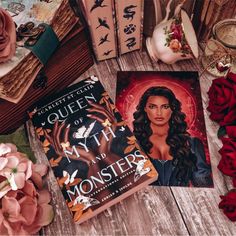 two books sitting on top of a wooden table next to flowers and other items in front of them