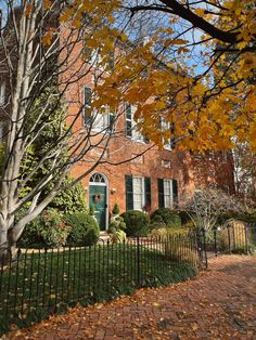 a red brick house surrounded by trees and leaves