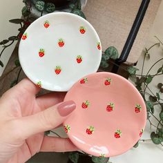 a hand holding two plates with strawberries on them