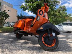 an orange scooter is parked in the parking lot