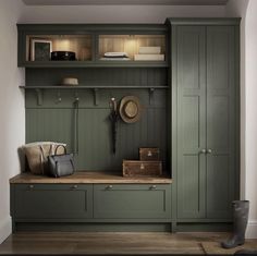 a room with green cupboards and wooden flooring next to a wall mounted coat rack