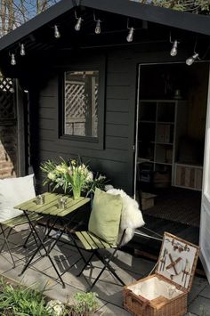 an outdoor patio with chairs, table and flowers on the side walk way in front of a house