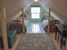 an attic bedroom with two beds and a rug on the floor in front of it