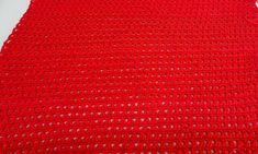 a red crocheted blanket laying on top of a white table