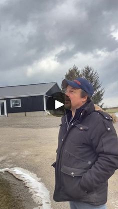 a man is standing in front of a building and talking to another man who is wearing a hat