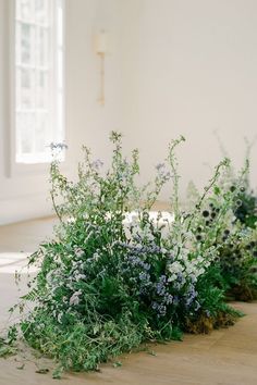 flowers and greenery are arranged on the floor next to each other in an empty room