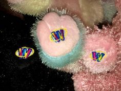 three different colored stuffed animals on a black surface with yellow, pink and blue decorations