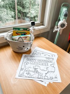 two coloring pages sitting on top of a wooden table next to a bowl of crayons