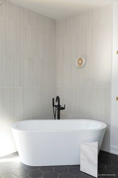 a white bath tub sitting in a bathroom next to a wall mounted faucet