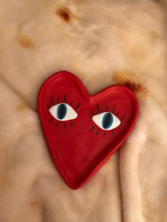 a red heart with blue eyes and eyelashes