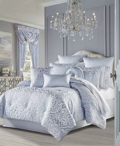 a bed with blue and white comforters in a bedroom next to a chandelier