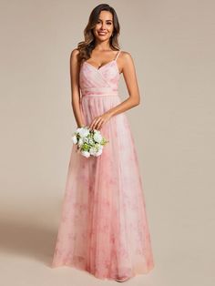 a woman in a long pink dress holding a white bouquet and smiling at the camera