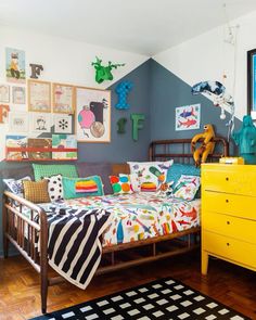 a bed room with a neatly made bed next to a yellow dresser and chest of drawers