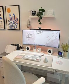 a desk with a computer monitor, keyboard and mouse on it in front of two pictures