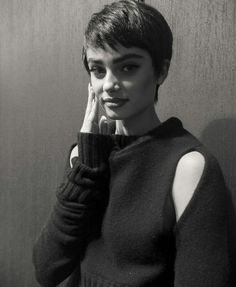 a black and white photo of a woman with her hand on her face, leaning against a wall