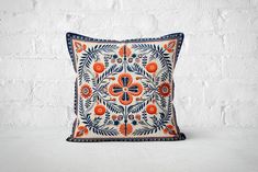 an orange and blue pillow on a white brick wall