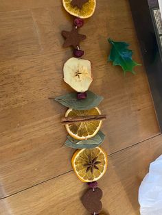 an arrangement of fruits arranged in the shape of a line on a wooden table with leaves and cinnamons