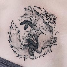 a woman's chest with a fox and roses tattoo on it, in black and white