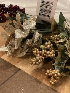 some gold and silver flowers on a wooden table next to other holiday decorating items