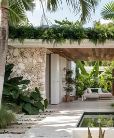 an outdoor living area with a pool surrounded by greenery