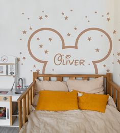 a bedroom with a mickey mouse decal on the wall and bed in front of it