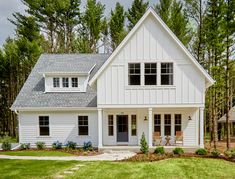 a white house in the woods with lots of windows