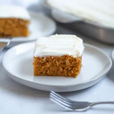 a piece of carrot cake on a white plate with a fork next to the slice