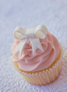 a cupcake with pink frosting and white bows