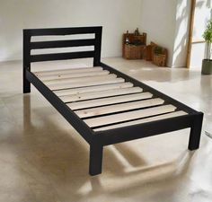 a black bed frame sitting on top of a white floor next to a potted plant