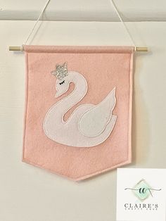 a pink towel with a white swan on it hanging from a clothes line next to a sign that says clairie's