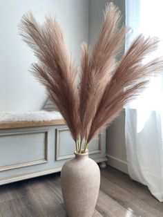 a white vase with some brown feathers in it