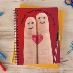 two fingers with faces drawn on them next to a notebook