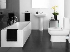 black and white bathroom with yellow basket in the floor next to the bathtub, sink, toilet and mirror