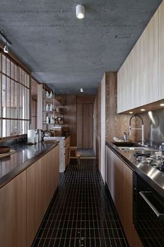 a long narrow kitchen with wooden cabinets and black counter tops